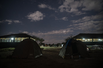 Fototapeta na wymiar Camping overnight in tents in savanna Serengeti camp during safari expedition. Amazing stars over tents