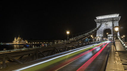Illuminated Szechenyi Chain Bridge at night in Budapest with Parliament in background and red smooth trace lights, Hungary