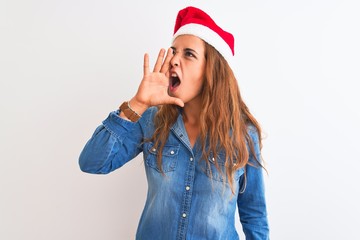 Young beautiful redhead woman wearing christmas hat over isolated background shouting and screaming loud to side with hand on mouth. Communication concept.