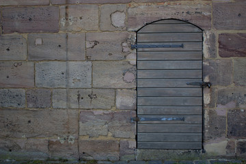 A wooden door against a stone wall. Walk near the Castle