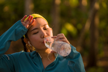 young Asian runner girl drinking water sweaty and tired. Attractive and exhausted Korean woman...