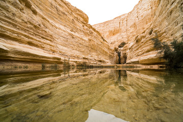 Small lake in Israeli mountains with water reflection. Surrounded with yellow rocks and clifs