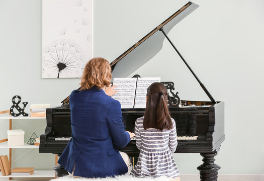 Man Teaching Little Girl To Play Piano