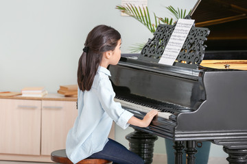 Little girl playing grand piano at home