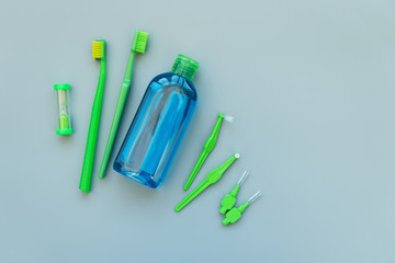 Top view on original, orthodontic, interdental, angle interdental toothbrushes, mouthrinse and timer on gray background. Healthy lifestyle. Flat lay