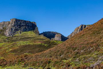 A scenic landscape on the Isle of Skye near The Old Man of Storr, with a clear blue sky overhead