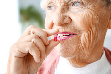 Elderly woman taking medicine at home, closeup