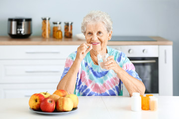 Elderly woman taking medicine at home