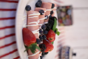 Rolls of canned ham stuffed with cheese served with seasonal fruit. Tasty traditional food