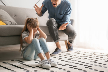 Angry father scolding his little daughter at home