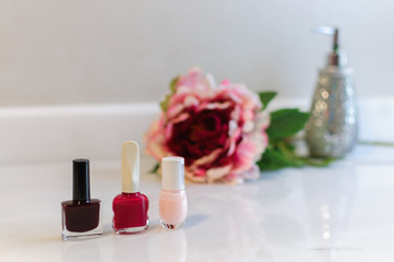 Obraz na płótnie Canvas group of nail polish of different colors and red rose in white marble
