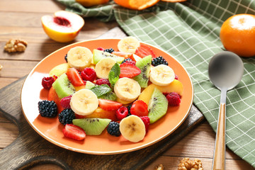 Plate with tasty fruit salad on table