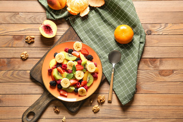 Plate with tasty fruit salad on wooden table