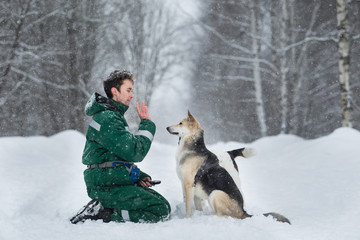 Two dogs walk outdoors in winter with an owner
