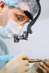 Close-up of a dentist surgeon's face with a microscope in glasses. Binocular glasses. Macro photo.