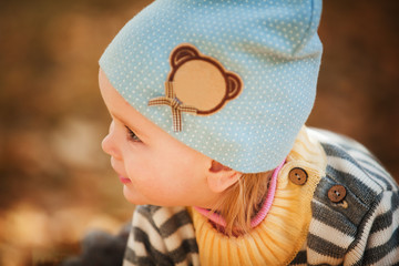 a child in a striped jacket and a blue hat close up