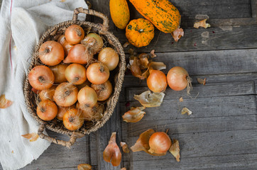 Onions in a basket - from above in a rustic vintage table with orange pumpkins and textured napkin - autumn background image