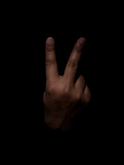Low key photo of a brown man showing the back of the hand with two fingers sticking out indicating the number two