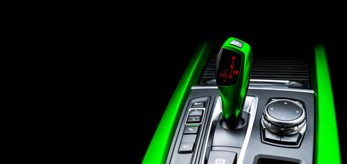 Green Automatic gear stick of a modern car. Modern car interior details. Car detailing. Automatic transmission lever shift isolated on black background. Black leather interior with stitching.