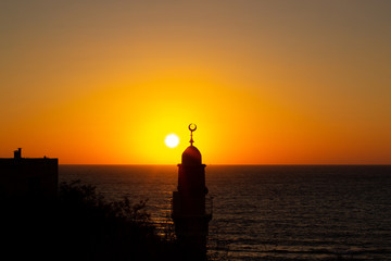religion country side sea waterfront scenic view of minaret tower silhouette on vivid orange sunset lighting background 