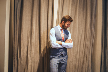 Handsome young businessman smiling while standing against grey background