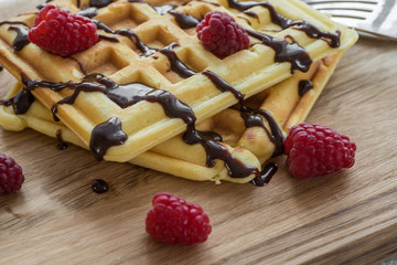 Two Viennese waffles with chocolate and berries on a wooden Board