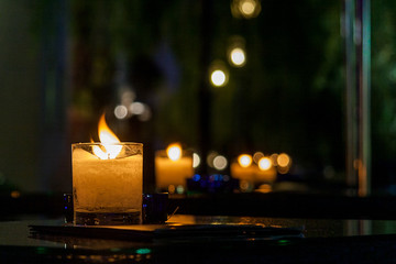 Close Up of burning candle in trasparent glasses on a black table