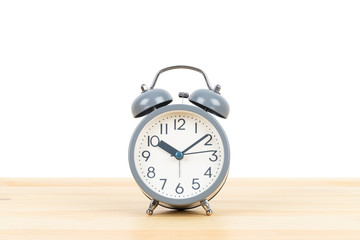Grey alarm clock on wooden desk on white background