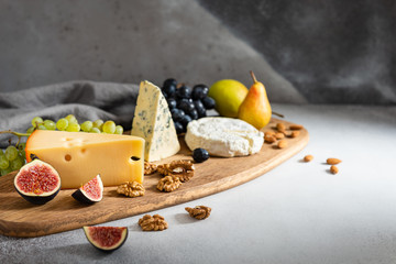 Cheese plate served with camembert, brie, blue cheese, maasdam, grapes, pear, figs and nuts on a...