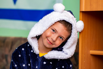 portrait of a boy in blue pajamas with a hood.