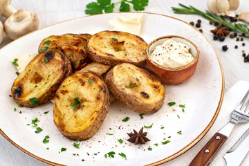 Rustic baked potato with cream sauce and spices on a serving platter. Copyspace