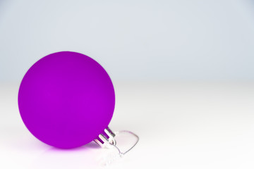 Single purple cristmas bauble on a white surface