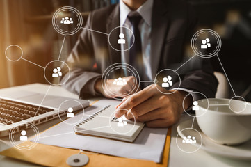 Social network theme hologram with businessman working on computer laptop, smartphone, and tablet with VR icons on background. 