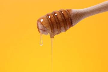 honey dripping from a wooden spoon for honey on a colored bright background.