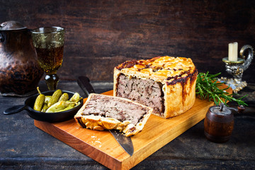 Traditional French Pate en croute with goose liver as closeup with gherkin and pepperoni on a...