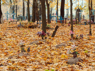 old wooden cross on a grave in a cemetery in autumn