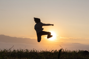 Silhouette of happy child jumping playing on mountain at sunset or sunrise