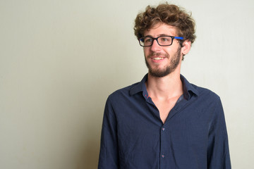 Face of happy young bearded businessman with eyeglasses thinking