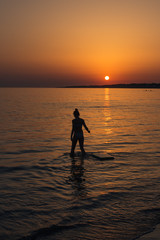 silhouette d'une femme à la mer avec un coucher de soleil