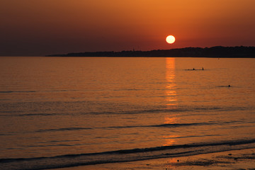 un coucher de soleil romantique sur la mer. Des baigneurs le soir. Des personnes se baignant avec...