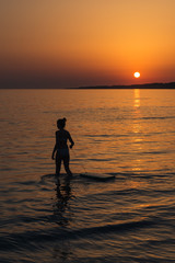 la silhouette d'une femme devant un coucher de soleil à lamer. Une surfeuse au coucher de soleil.