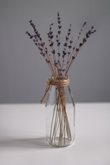 transparent vase in Scandinavian style with dried flowers purple on a light background and a white table vertical photo