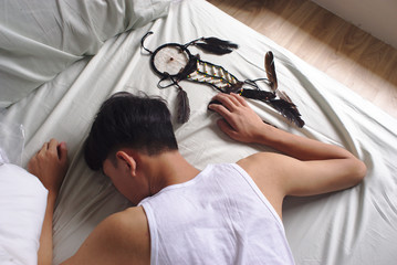Asian man sleeps while holding dream catcher