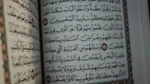 flipping the pages of the holy Quran muslim holy book, detail of surah in slow motion, Holy Quran Kareem on wooden background with copy space, ramadan Kareem concept,