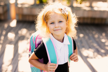Happy little schoolgirl with school bag in school garden. Back to school outdoor