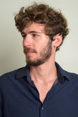 Face of young bearded businessman with curly hair thinking