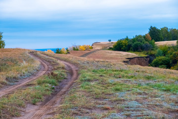 Grassy cliffs with a road that curves around the green fields, against the sky and river