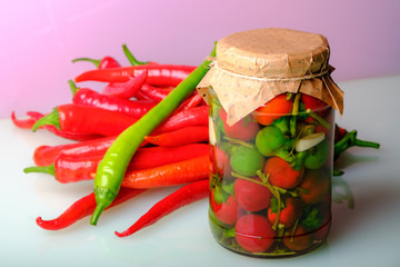 composition of pickled hot pepper in a glass jar and fresh peppers