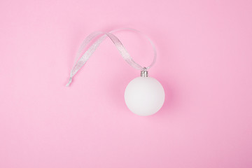 Christmas decoration on the Christmas tree white glass ball on a pink background, flat lay,copy space,minimalism concept,