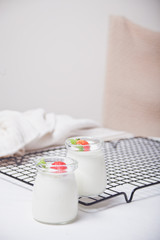 Fototapeta na wymiar Two portions natural homemade yogurt in a glass jar with fresh strawberry on the white background
